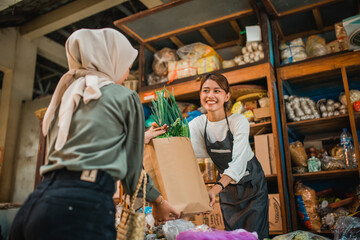happy female green grocery seller giving customer vegetables