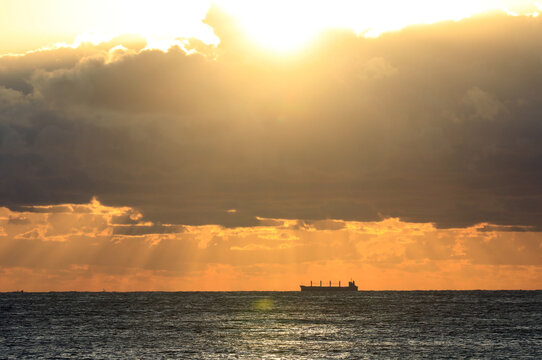 commercial cargo ship in the sun and dark clouds
