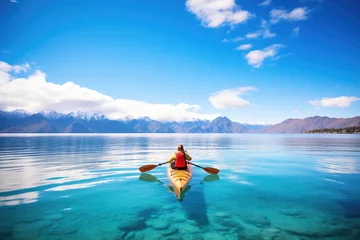 Foto op Canvas a man kayaking in a clear ocean bay with mountains © Natalia