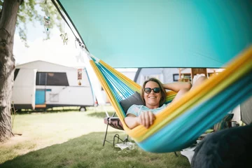  woman relaxing in hammock beside mobile tiny home © Natalia