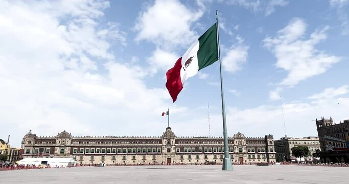 slow motion shot of mexican flag flying on the zocalo in front of national palace at midday