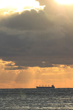 commercial cargo ship sailing in the sun and dark clouds