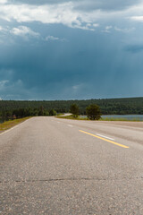Highway towards the storm rising, dramatic clouds ahead. Image taken from low point of view on the asphalt road. - 709563439