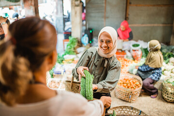female customer buying fresh vegetables from traditional farmer market