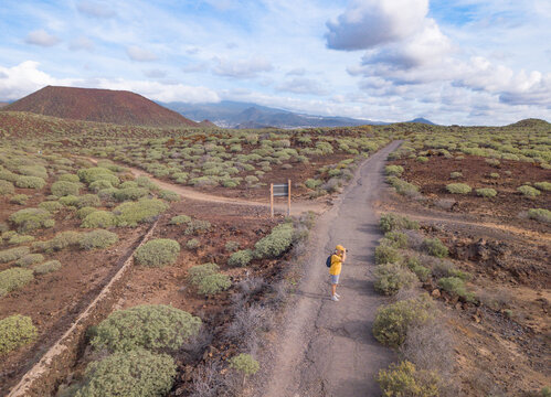 Aerial view of mature traveler woman walking in outdoors protected area in south of Tenerife taking pictures. People and weekend tourism leisure outdoor activity, concept lifestyle.