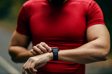 Close up of sportsman's hand using a smart watch in nature.