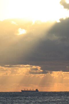 commercial cargo ship sailing in the sun and dark clouds