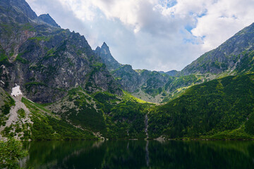 Fototapeta na wymiar Amazing view on mountains range near beautiful lake at summer day. Tatra National Park in Poland. Panoramic view on Morskie Oko or Sea Eye lake in Five lakes valley
