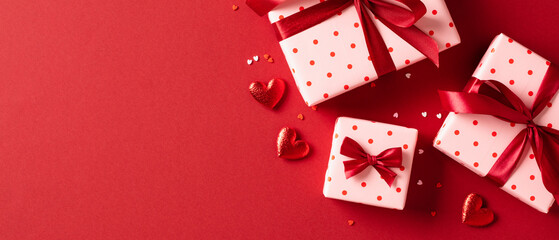 Valentines Day banner design. Top view gift boxes with red ribbon bows, hearts, confetti on red background - obrazy, fototapety, plakaty
