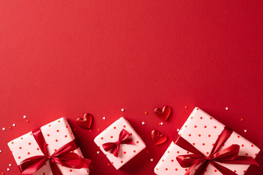 Valentines Day gifts with red hearts on red table. Top view, flat lay.