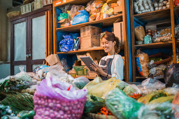 happy female green grocery seller checking product using tablet