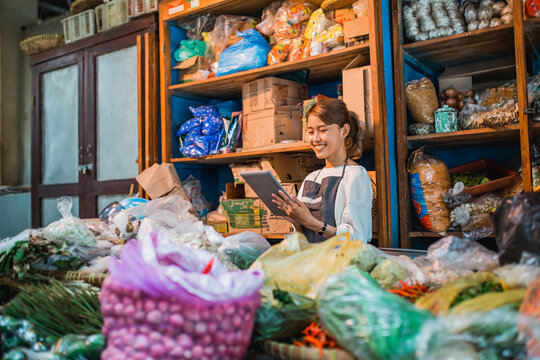 happy female green grocery seller checking product using tablet - Powered by Adobe