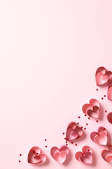 Paper cut hearts and confetti on vertical pink background. Valentine's Day concept.
