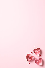 Valentine's day vertical background with paper cut hearts on pink. Flat lay, top view.