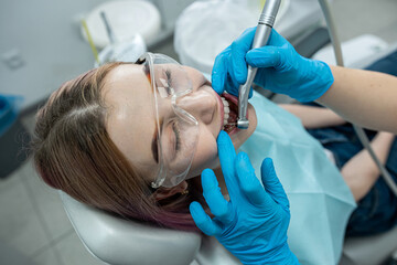 young girl sits in a medical chair while a dentist treats her teeth in a dental clinic.