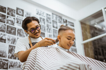 asian male client getting hair cut by professional and friendly hairdresser in barbershop