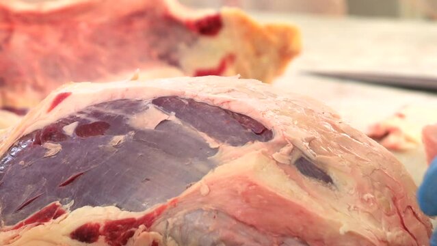 Macellaio taglia un pezzo di grasso dalla carne.
Primo piano della lama del coltello che taglia il grasso delle carne in macelleria.