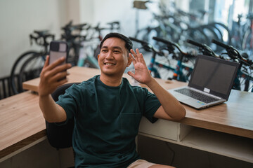 young man makes video call using cell phone while working at desk