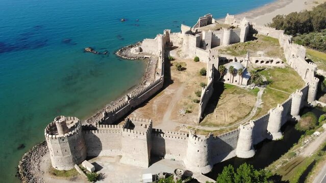 Picturesque drone view of remains of medieval castle Mamure Kalesi in Bozdogan village on coast near turquoise waters of Mediterranean Sea on sunny spring day, Turkey