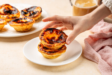 Eating pastel de nata or pastel de Belem, Portuguese baked egg custard tart pastry. Girls hand...
