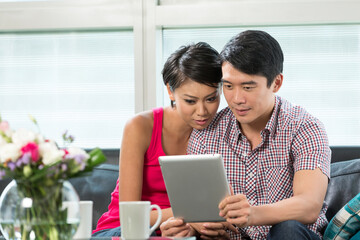 Young Chinese couple using a digital tablet