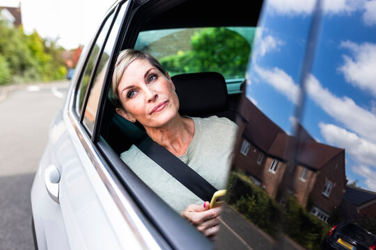 Mature woman leaning on window sitting in car