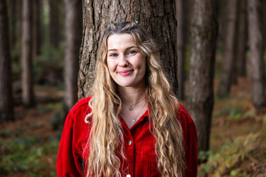 Smiling young beautiful woman near tree in forest
