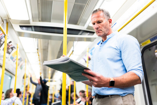 Mature businessman reading newspaper on train
