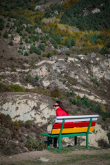 Girl on the background of mountains sitting on a bench