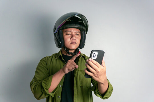 Adult Asian man confusing when looking to his handphone while wearing motorcycle helmet