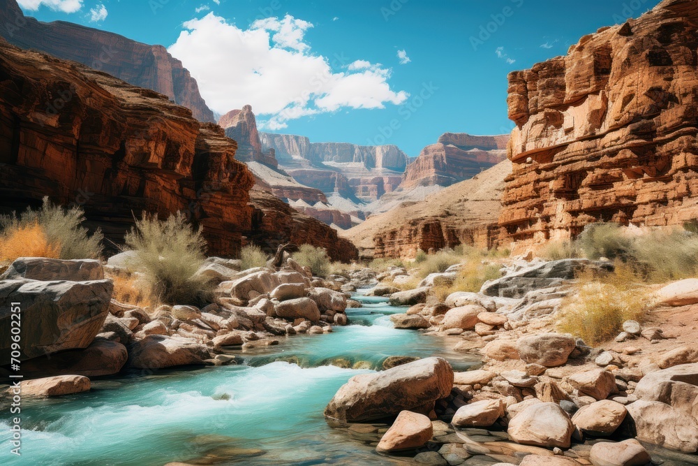 Poster  a river running through a canyon surrounded by rocks and a sky with some clouds in the background and a few bushes in the foreground.