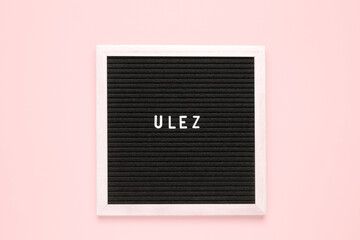 The word ulez on black letter board over isolated beige background