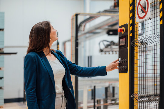 Businesswoman touching push button on control panel in industry