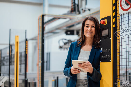 Smiling businesswoman with tablet PC in industry