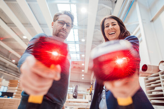 Happy colleagues with illuminated bar code readers standing in industry