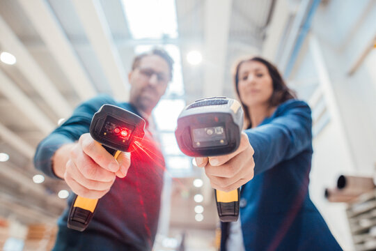 Colleagues with illuminated bar code readers standing in industry