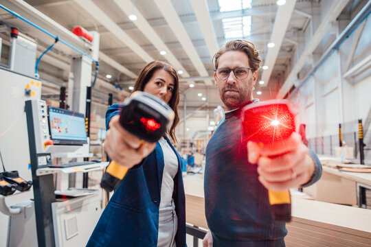 Confident colleagues with illuminated bar code readers standing in workshop