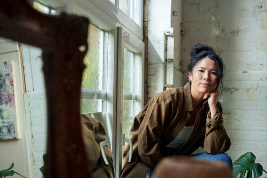 Woman leaning on elbows sitting by window