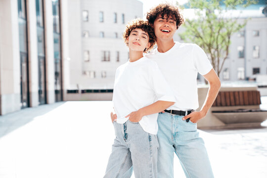 Young smiling beautiful woman and her handsome boyfriend in casual summer white t-shirt and jeans clothes. Happy cheerful family. Female having fun. Couple posing in street at sunny day