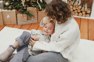 Mother embracing smiling son on white carpet at home
