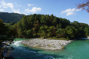 Fototapeta premium The blue river flows through the forest of Shirakawago Village, Japan.