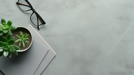 Serene Workspace with Stylish Arrangement: Notebook, Green Plant, Glasses, Coffee Cup, and Black Pen on Grey Background for Minimalistic Office Concept