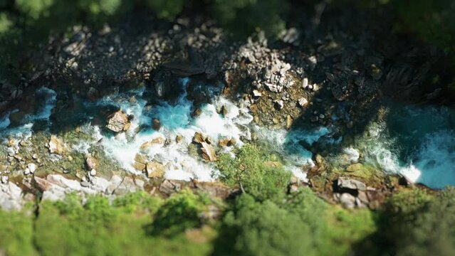 A shallow mountain river rushes through the rocky canyon. Aerial view.