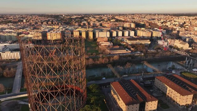 Alba sul Gazometro del quartiere post industriale Ostiense a Roma, Italia.
Veduta aerea con drone dei raggi del sole che passano attraverso la vecchia struttura del Gasometro.
