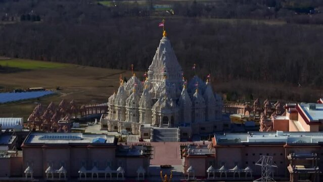 An aerial view of the Shri Swaminarayan Mandir in Robbinsville Twp, NJ on a sunny day, it was closed for the day. The camera dolly in towards the engraved temple.