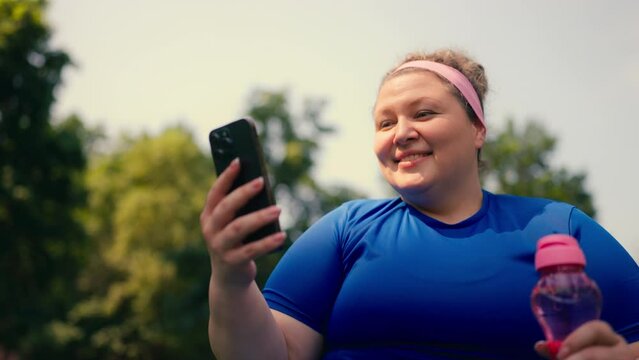 Happy overweight woman using mobile fitness app, happy with workout results