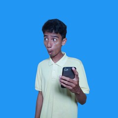 Young Asian man surprised looking at smart phone screen, purple background.