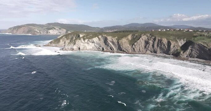 Aerial drone shot of Atlantic Ocean waves coming into shore at beach in Sopela outside of Bilbao, Basque, Spain, Europe. Drone orbiting. Shot in ProRes 422 HQ