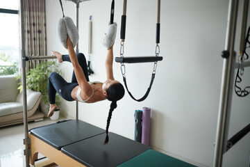 Fototapeta premium Fit young woman upside down pull-ups in special machine