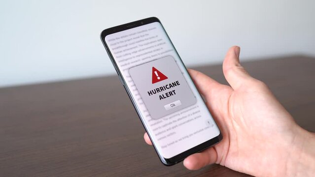 Hurricane alert notification appearing on the phone while in use. Bad weather and strong wind concept.
